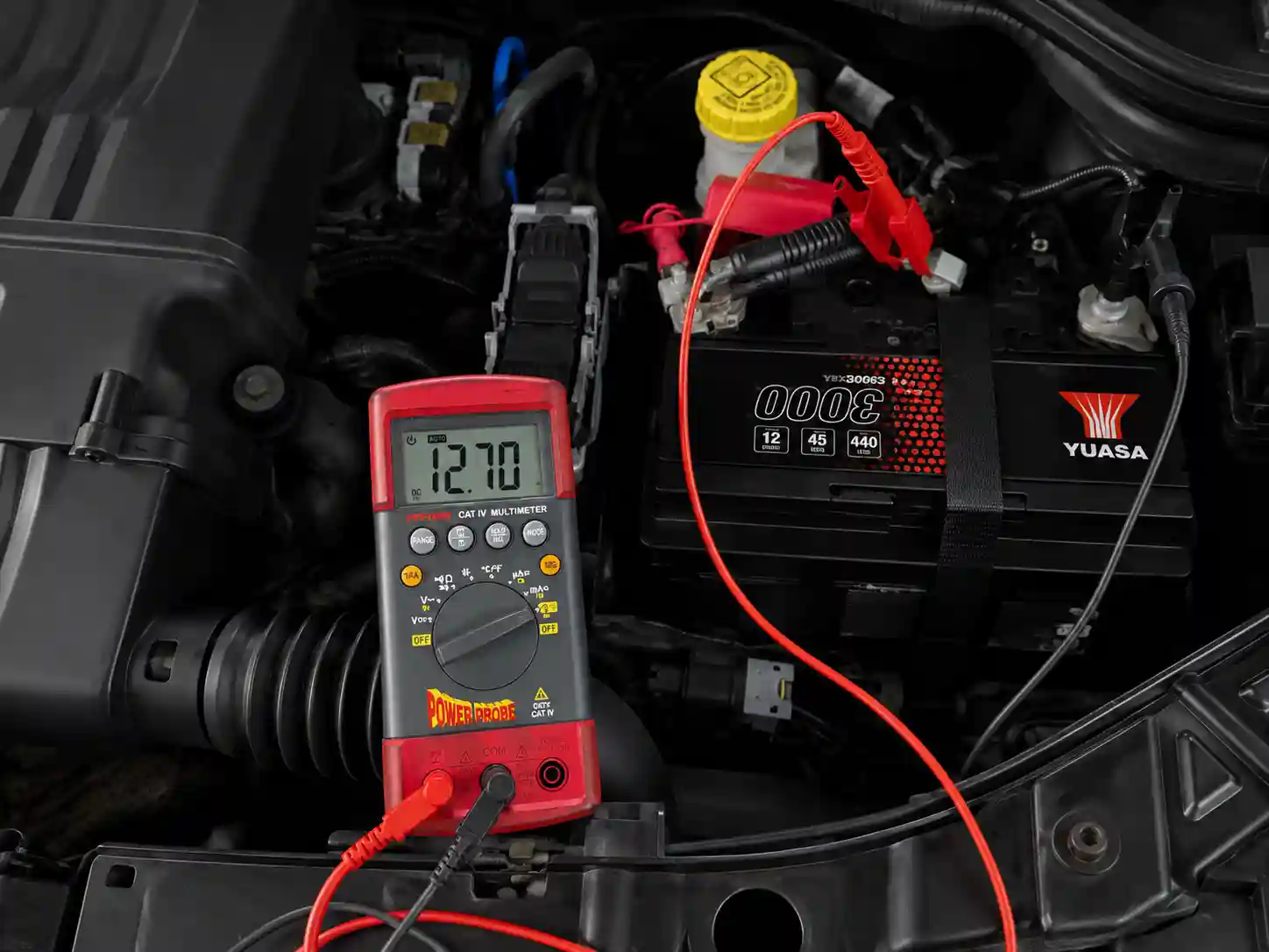 Technician testing a 12V car battery with a multimeter
