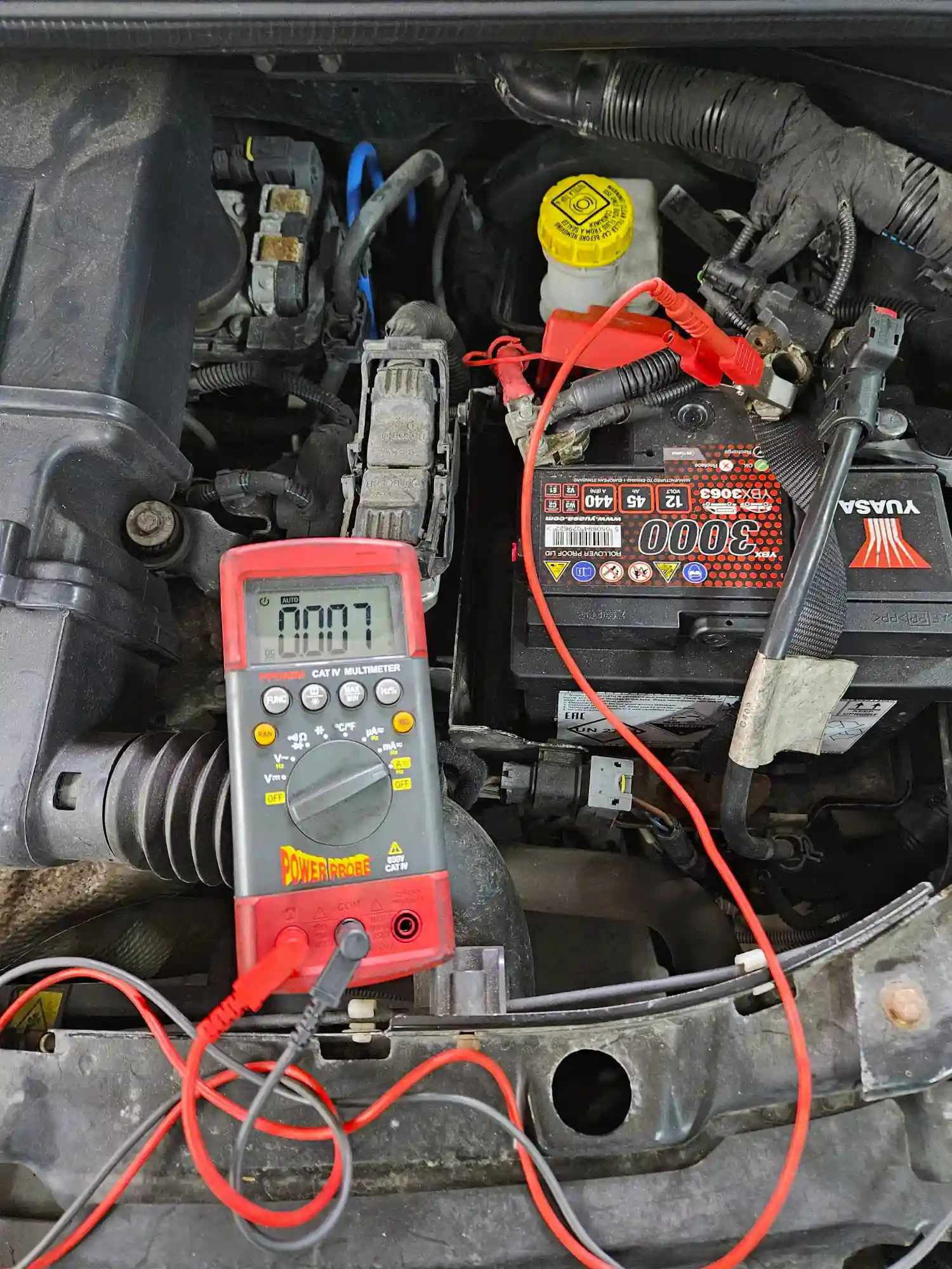 Car battery being tested with a multimeter to trace a battery drain fault