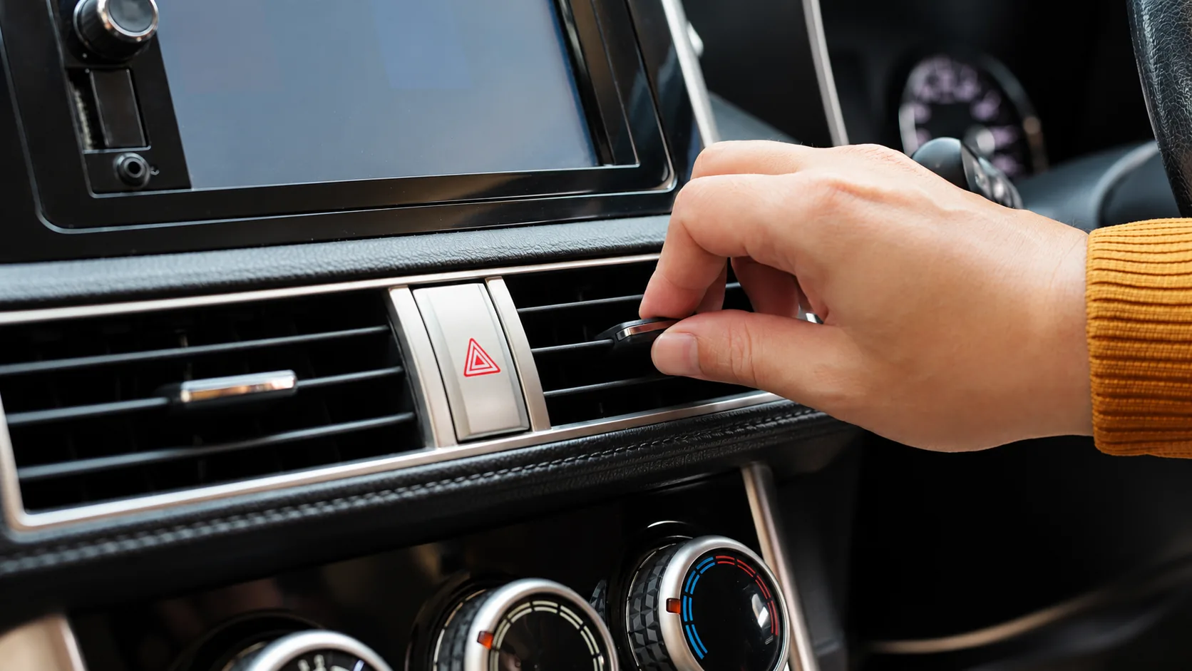 Driver adjusting the car air conditioning controls