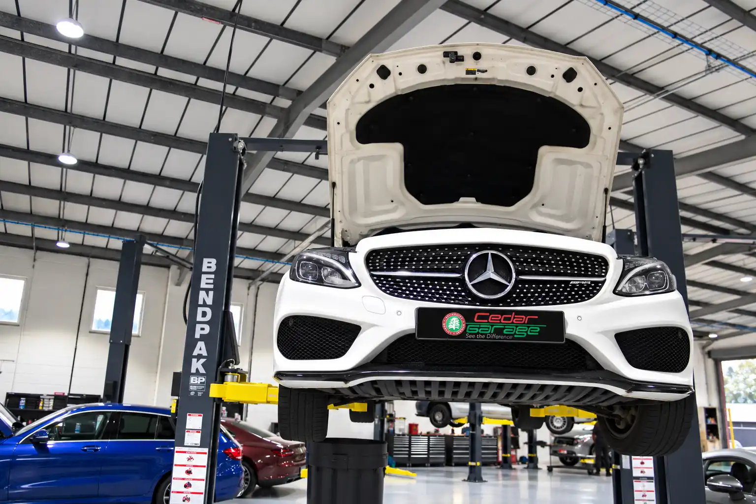 Mercedes on a vehicle lift at Cedar Garage, ready for smoke and leak testing